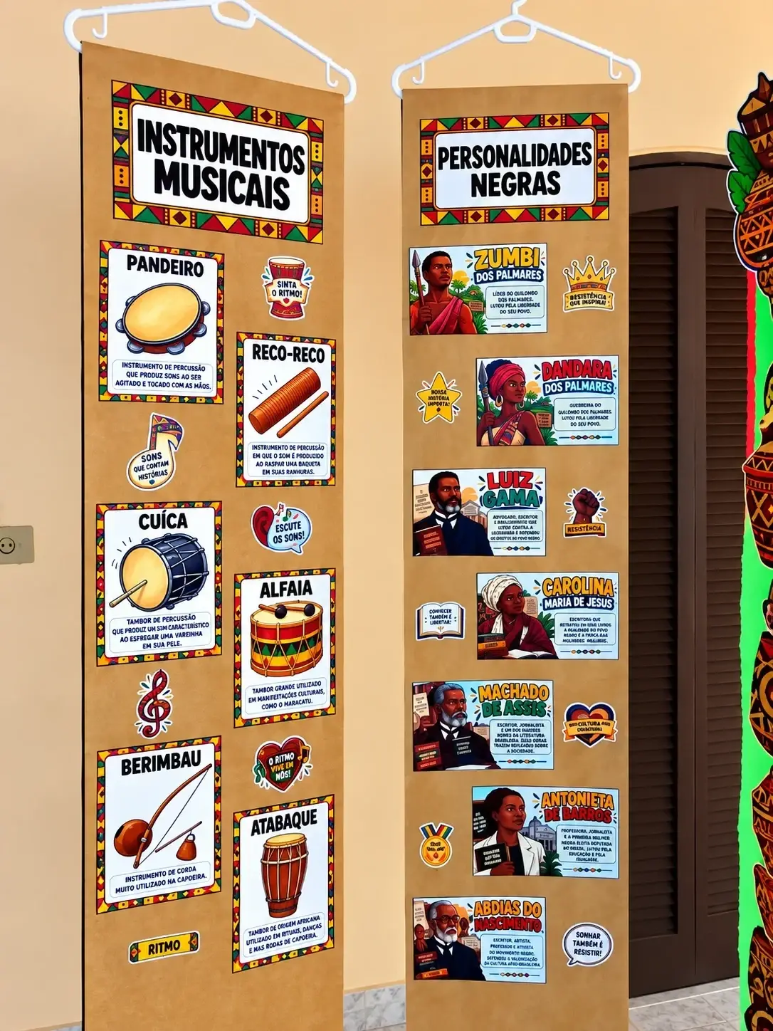 Banners 'Instrumentos Musicais' e 'Personalidades Negras' pendurados em cabides
